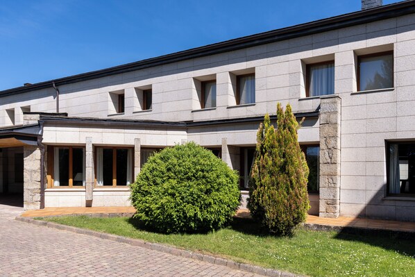 A modern building with a flat roof, multiple windows, and a paved entrance area.