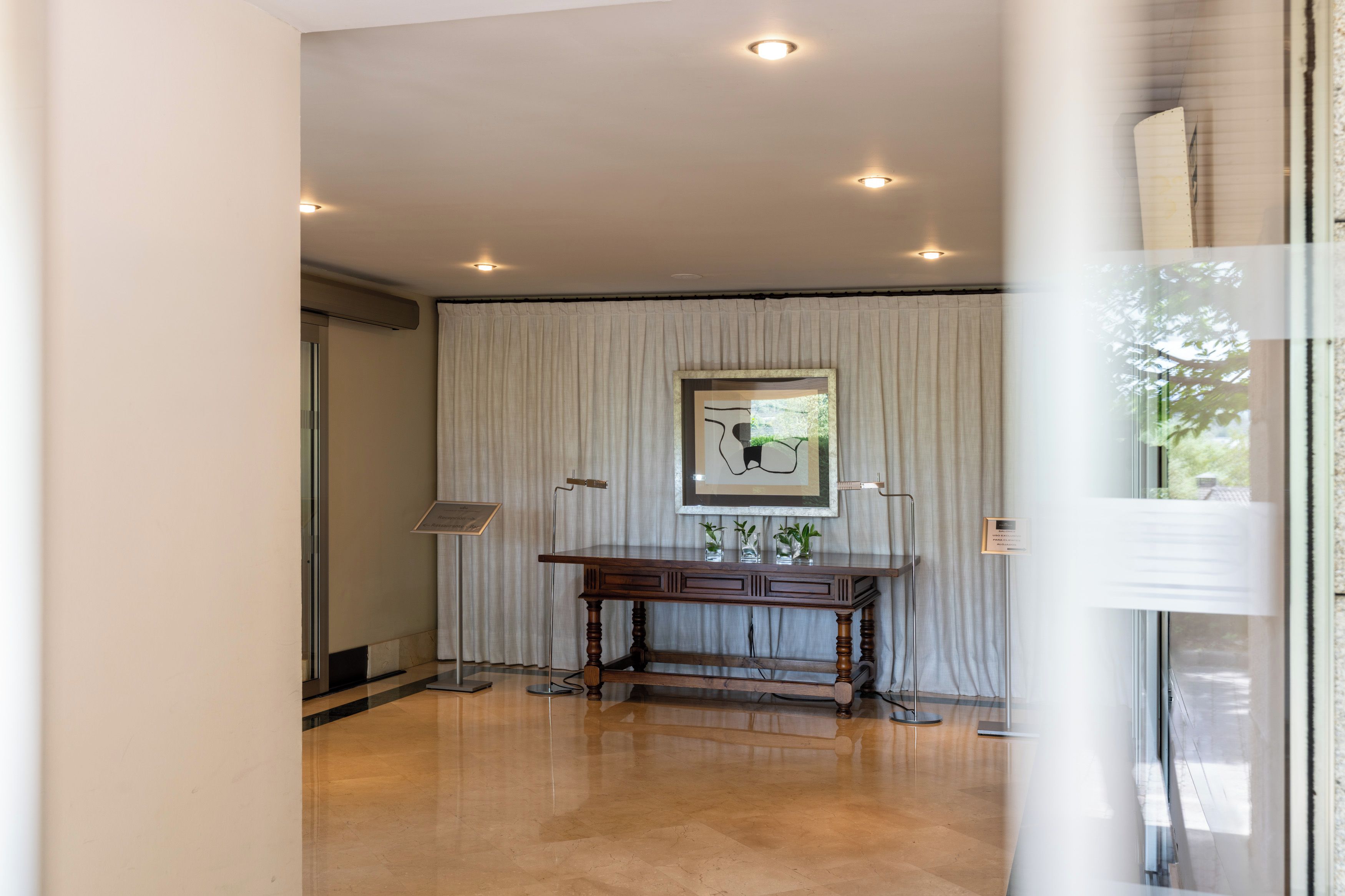 A room with a wooden desk, a framed artwork, and a floor lamp.