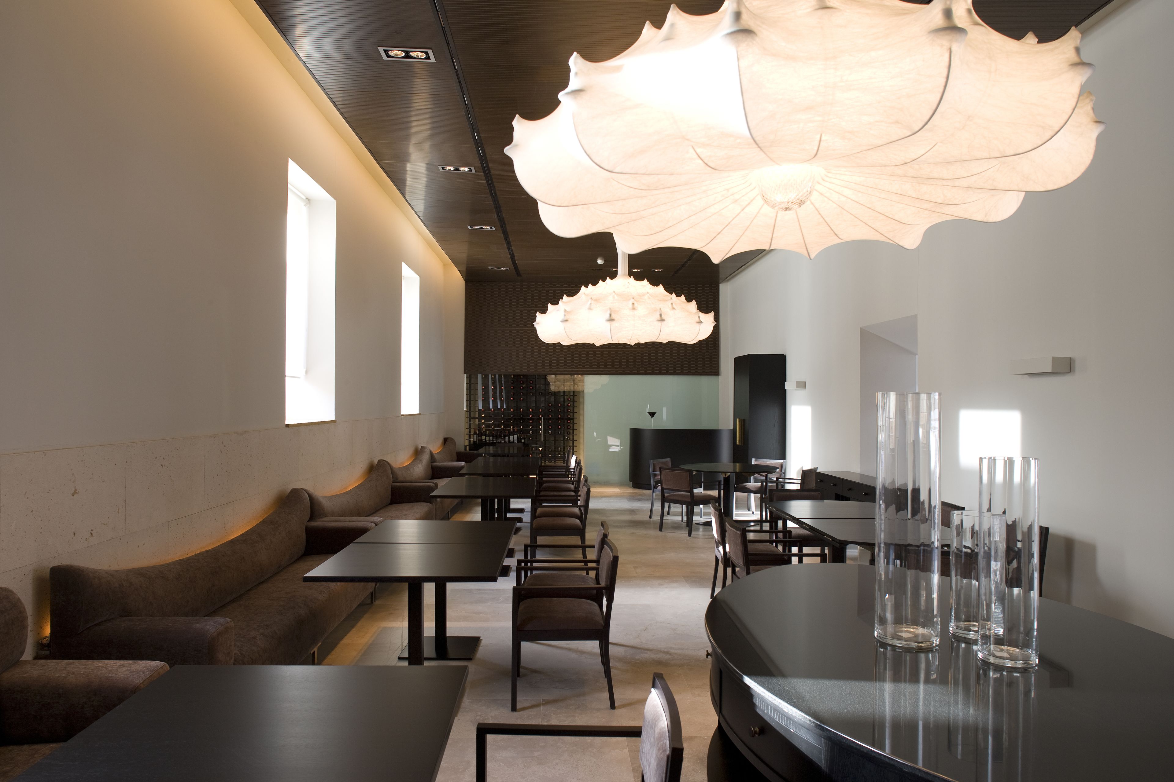 A modern interior with seating areas, tables, and a unique ceiling light fixture.