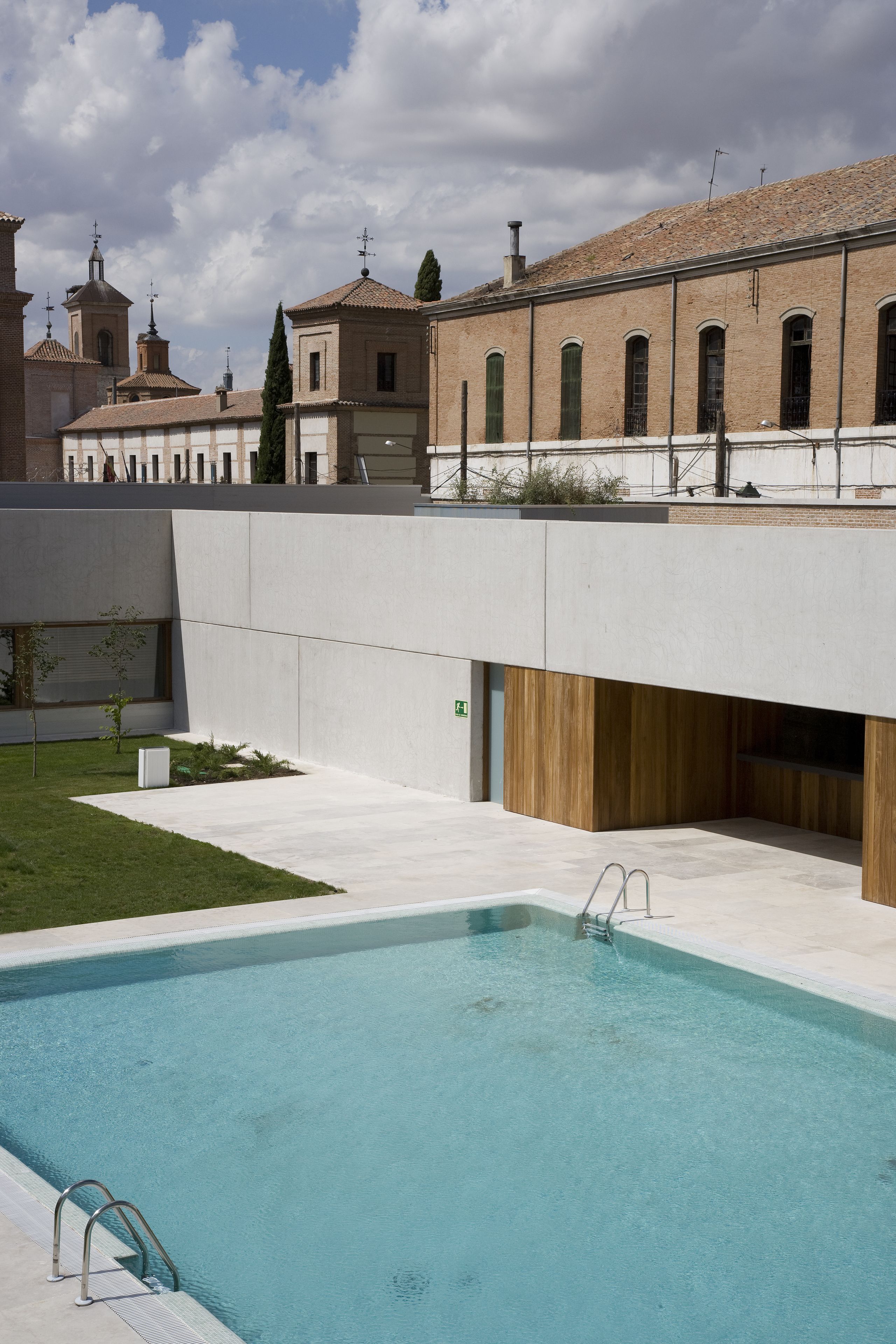 Una piscina de diseño moderno, rodeada por un solárium de hormigón y una estructura de madera.