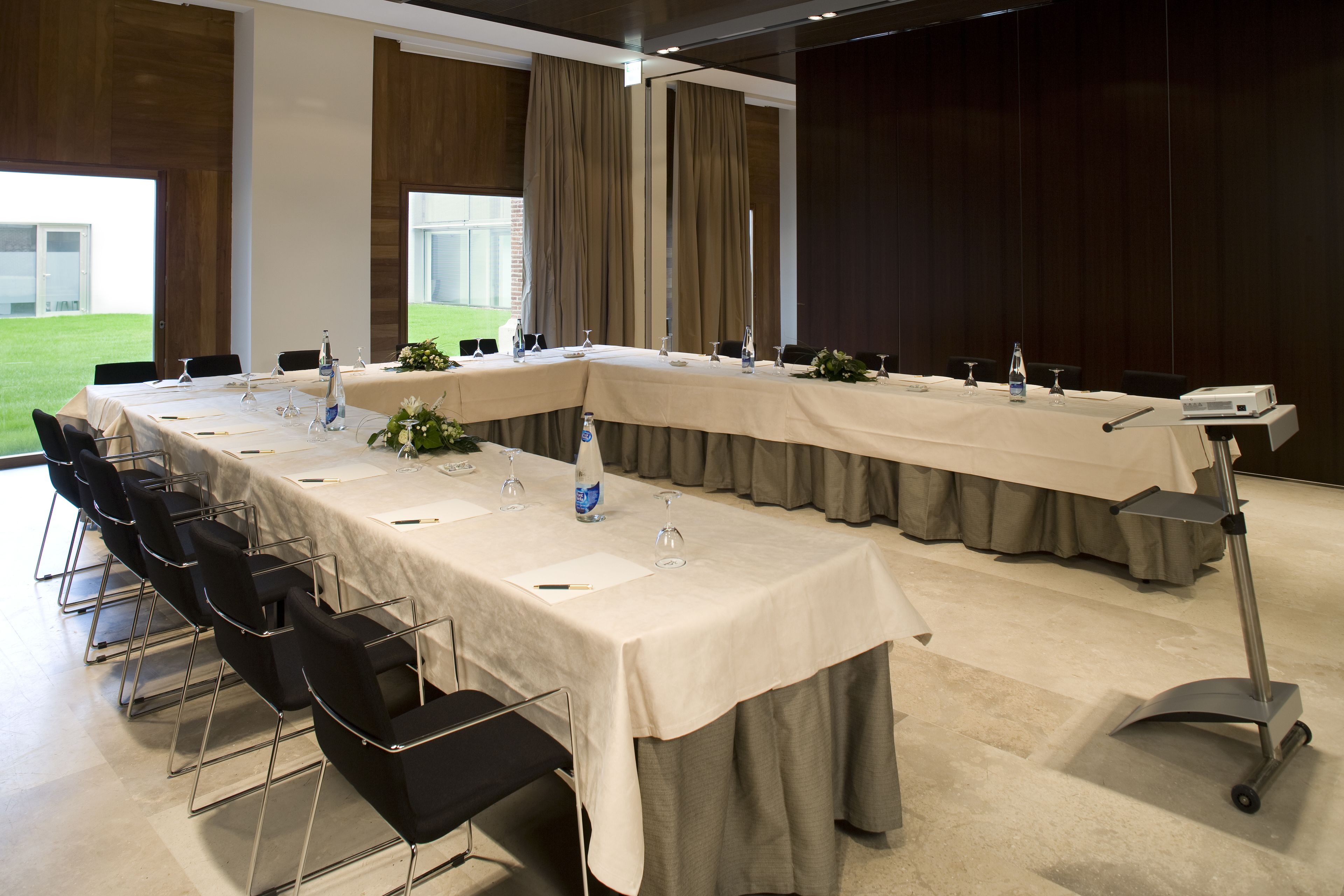 Un salón de conferencias con una larga mesa, sillas y un proyector.
