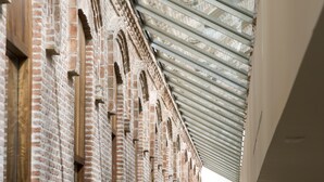 A corridor with a high ceiling and skylight, featuring brick walls and a modern interior design. - Parador De Alcala (Alcala de Henares)