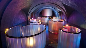 A tunnel-like interior with cylindrical structures, possibly for lighting or decoration, and a large, illuminated object in the background. - Parador De Alcala (Alcala de Henares)