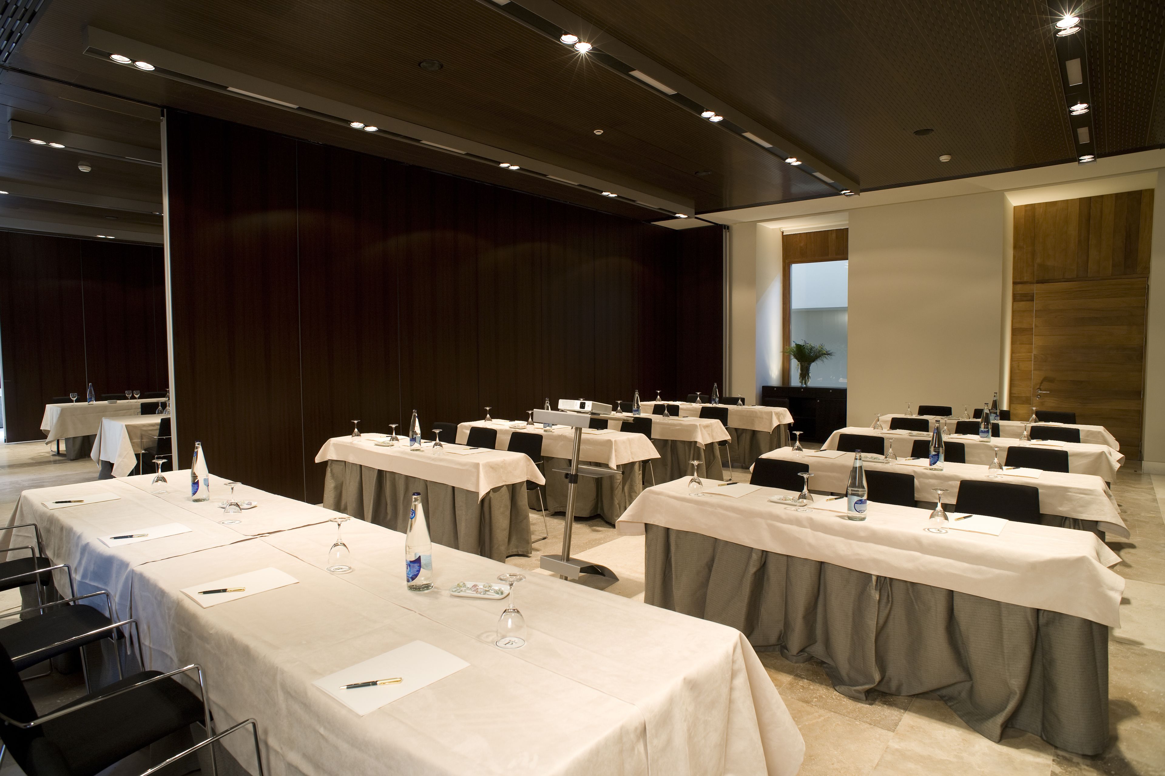 Un salón de conferencias con varias mesas, cada una con tarjetas de identificación, botellas de agua y vasos.