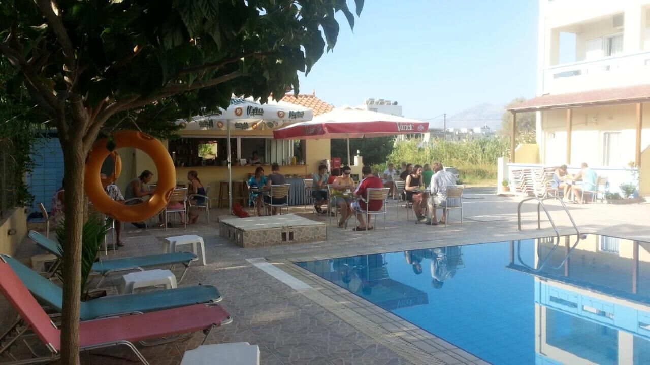 Zona junto a la piscina con sillones de descanso, bar y sombrillas.