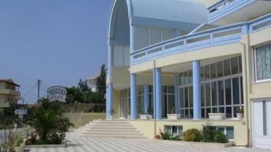 A modern building with a large entrance, multiple columns, and a staircase leading to the entrance. - Eleni Palace (Malevizi)