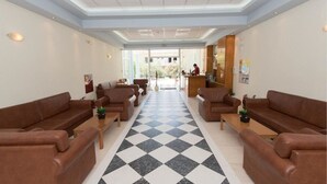 A hotel lobby with a checkered floor, leather sofas, and a reception desk. - Eleni Palace (Malevizi)