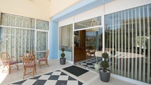 A hotel entrance with a check-in desk, a seating area with chairs and potted plants, and a checkered floor pattern. - Eleni Palace (Malevizi)