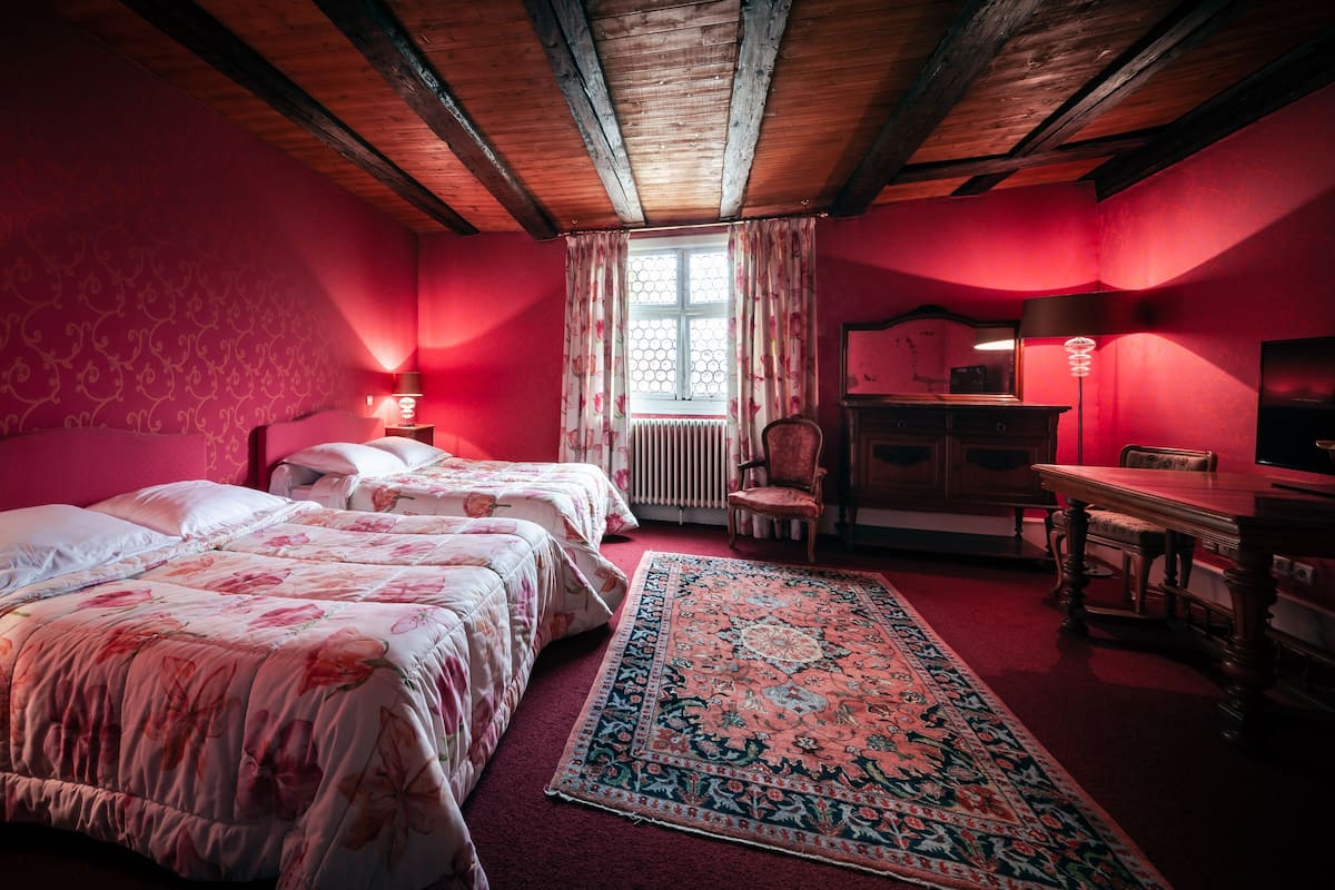 Quarto com duas camas, uma escrivaninha e uma cadeira.