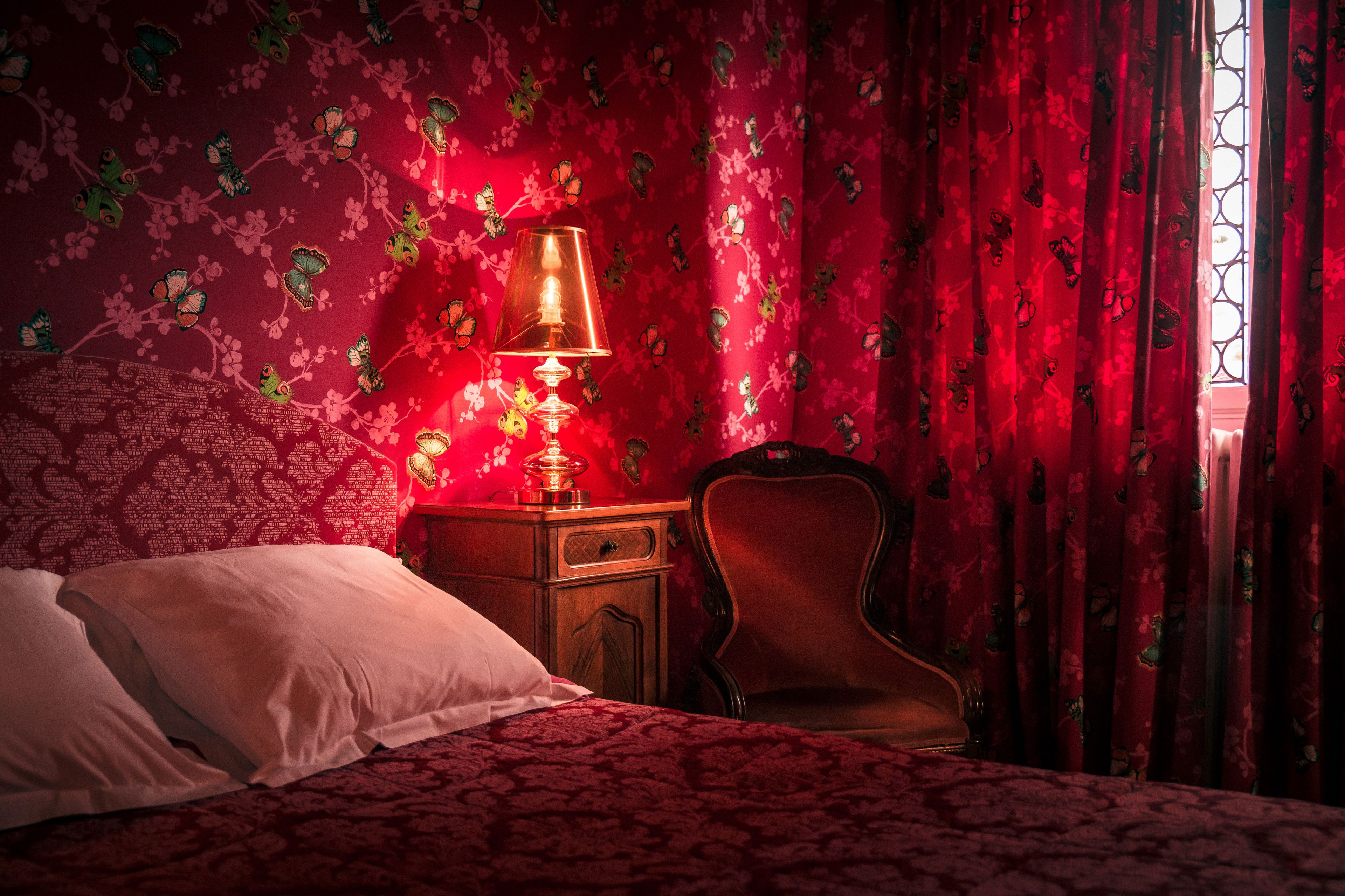 A bedroom with a bed, a nightstand with a lamp, and a chair.
