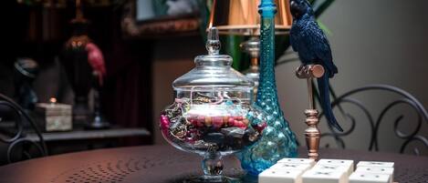 A table with a glass jar filled with colorful beads, a blue decorative item, and a wooden domino set.