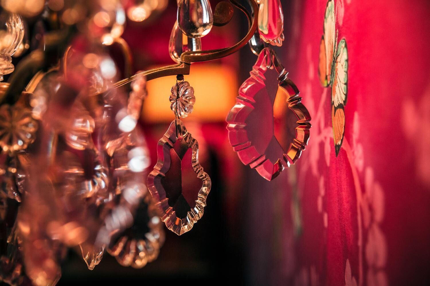 A close-up of a decorative glass ornament with a floral design, suspended from a metal hook.