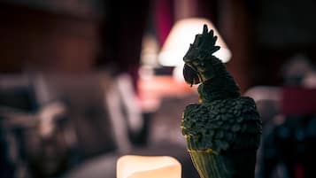 A parrot figurine in a dimly lit room with a candle.