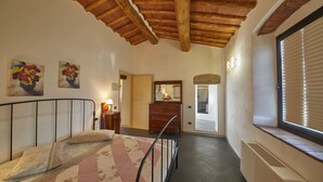 A bedroom with a bed, a dresser, a mirror, and a window with blinds. - Colle Da Vinci (Vinci)
