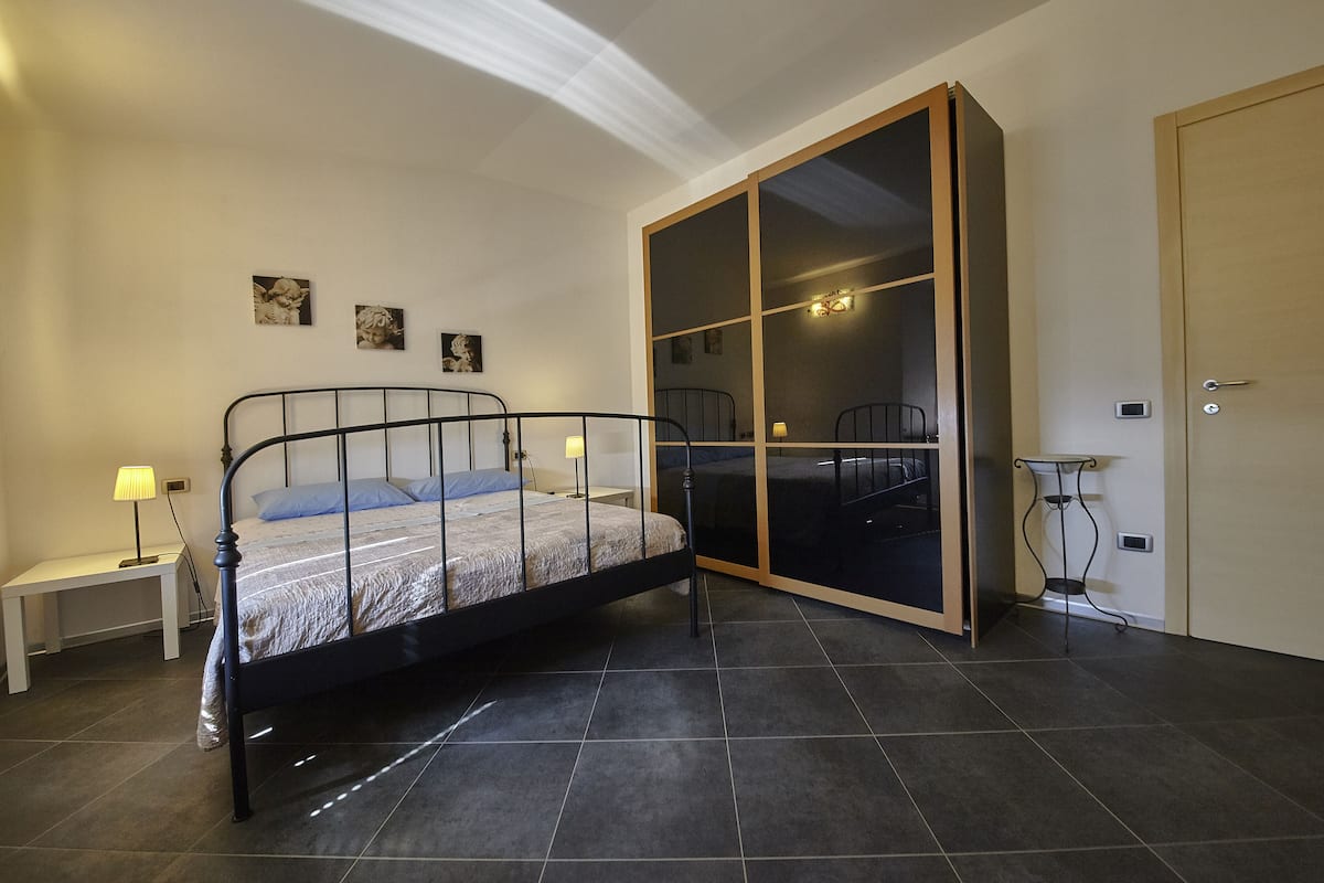 Ein Schlafzimmer mit einem Bett, einem Kleiderschrank, einem Nachttisch und einem Beistelltisch.