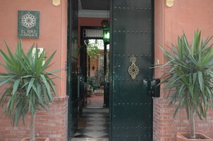 Una puerta verde con macetas a ambos lados y un suelo de baldosas.