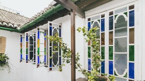 A traditional building with a tiled roof, a wooden balcony, and a potted plant. - EL Riad Andaluz - Guest House (Málaga)