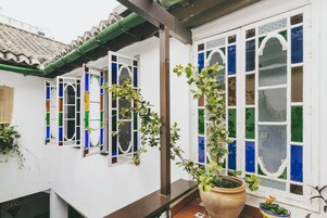 Un edificio tradicional con techo de tejas, balcón de madera y una planta en maceta.
