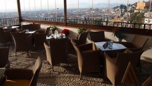 A terrace with wicker furniture and a view of a cityscape. - Hotel Mirador Arabeluj (Granada)