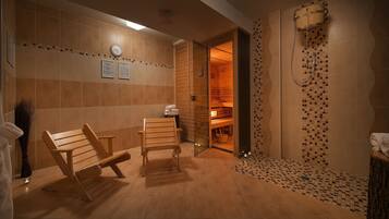 Un cuarto de sauna con bancos de madera, suelo de baldosas y zona de ducha con diseño de mosaico.