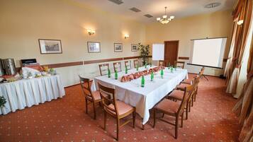 A conference room with a long table, chairs, a whiteboard, and framed pictures on the walls.