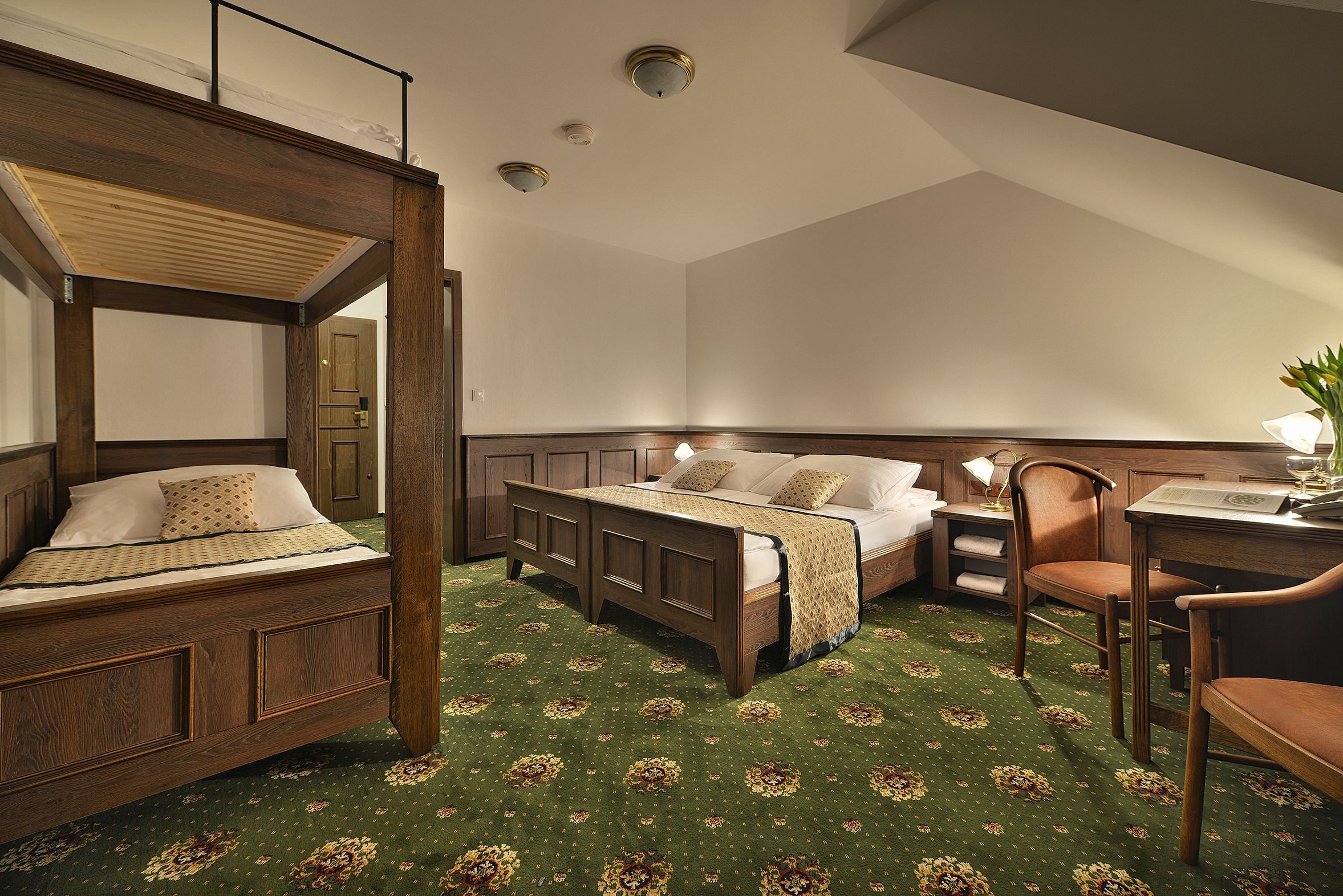 A room with a four-poster bed, a desk, and a chair.