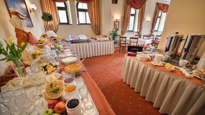 Un buffet de petit-déjeuner proposant une variété d’aliments et de boissons, disposés sur des tables recouvertes d’un tapis rouge.