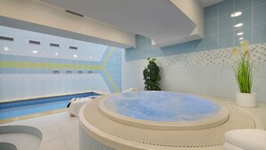 Un espace spa moderne doté d’un jacuzzi, d’une piscine et d’un mur carrelé orné d’un motif géométrique.