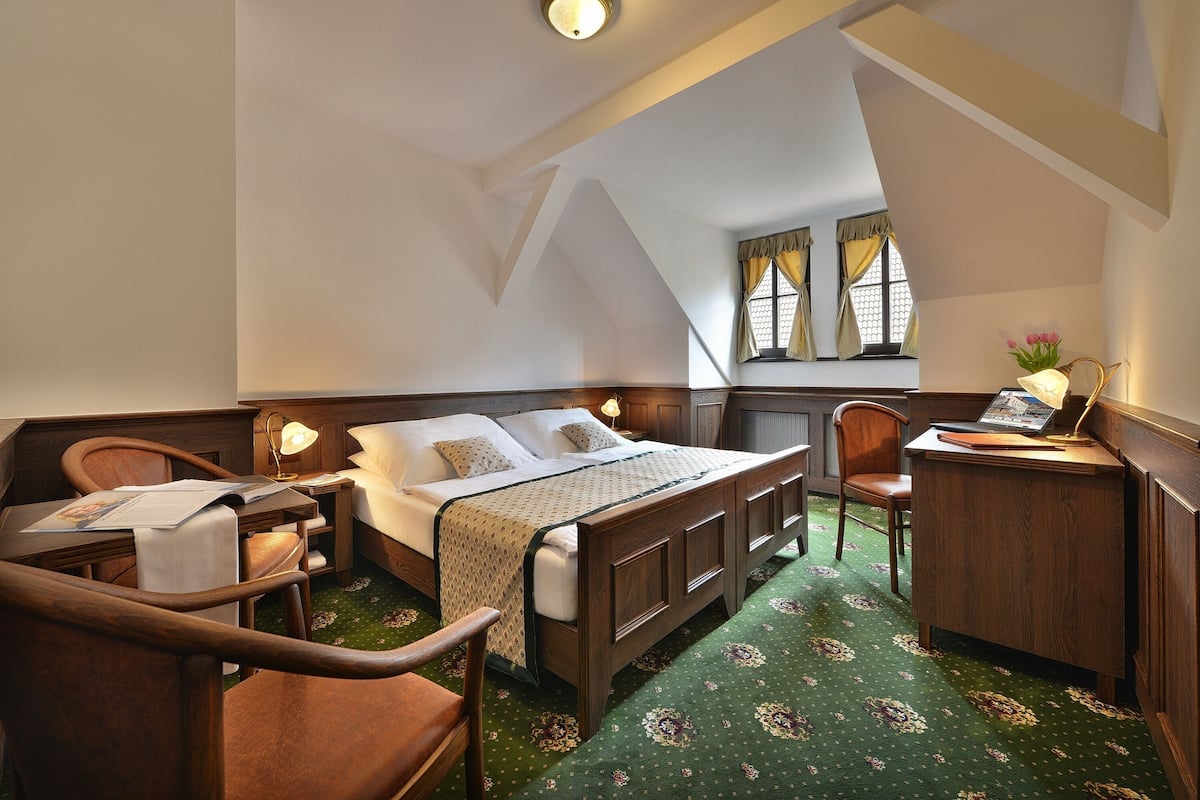 Ein Schlafzimmer mit Bett, Schreibtisch, Stuhl und einem Fenster mit Vorhängen.