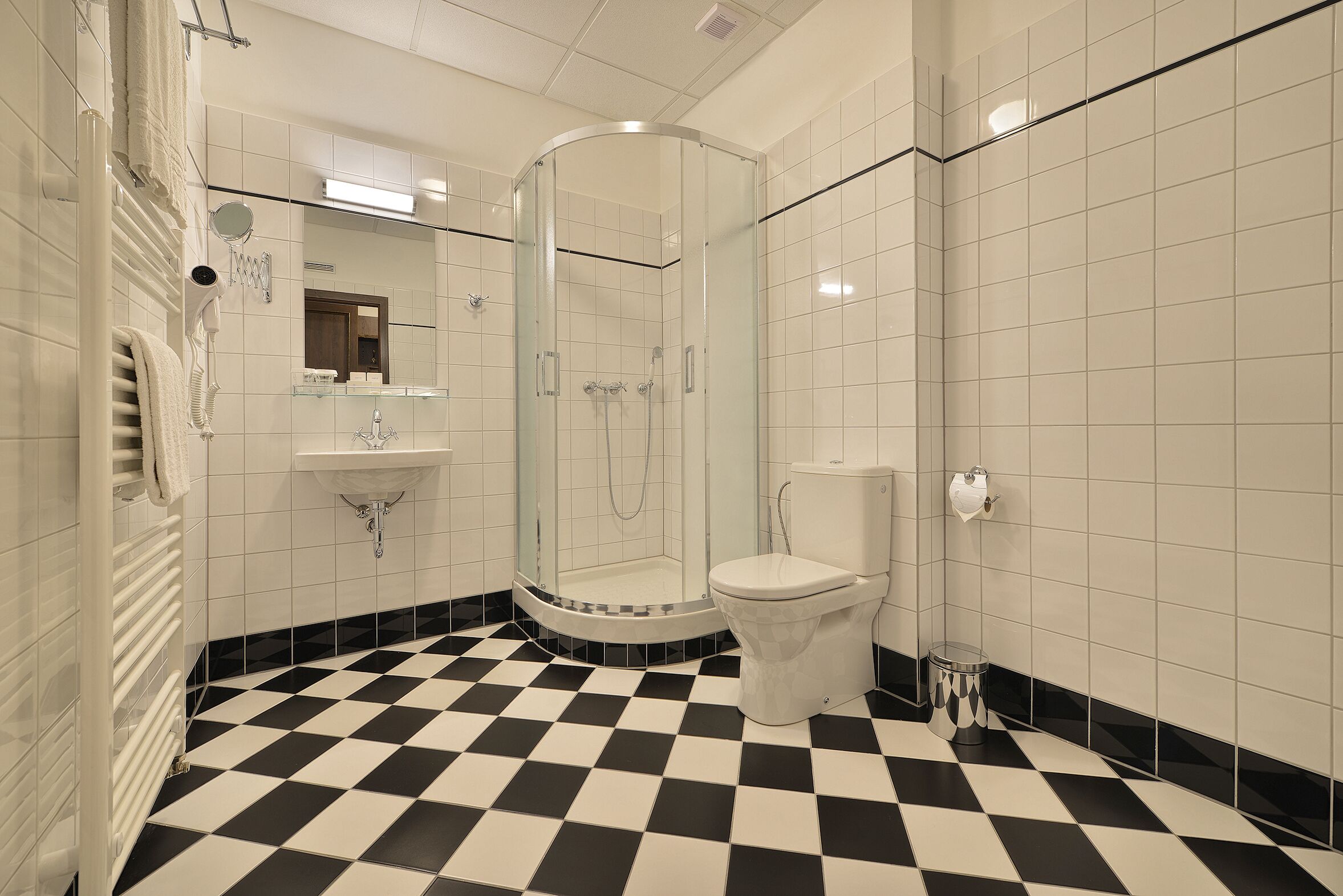 A bathroom with a glass-enclosed shower, a toilet, and a sink.