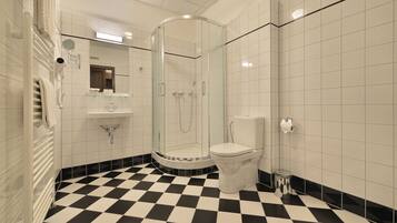 Et badeværelse med bruseniche, toilet og håndvask.