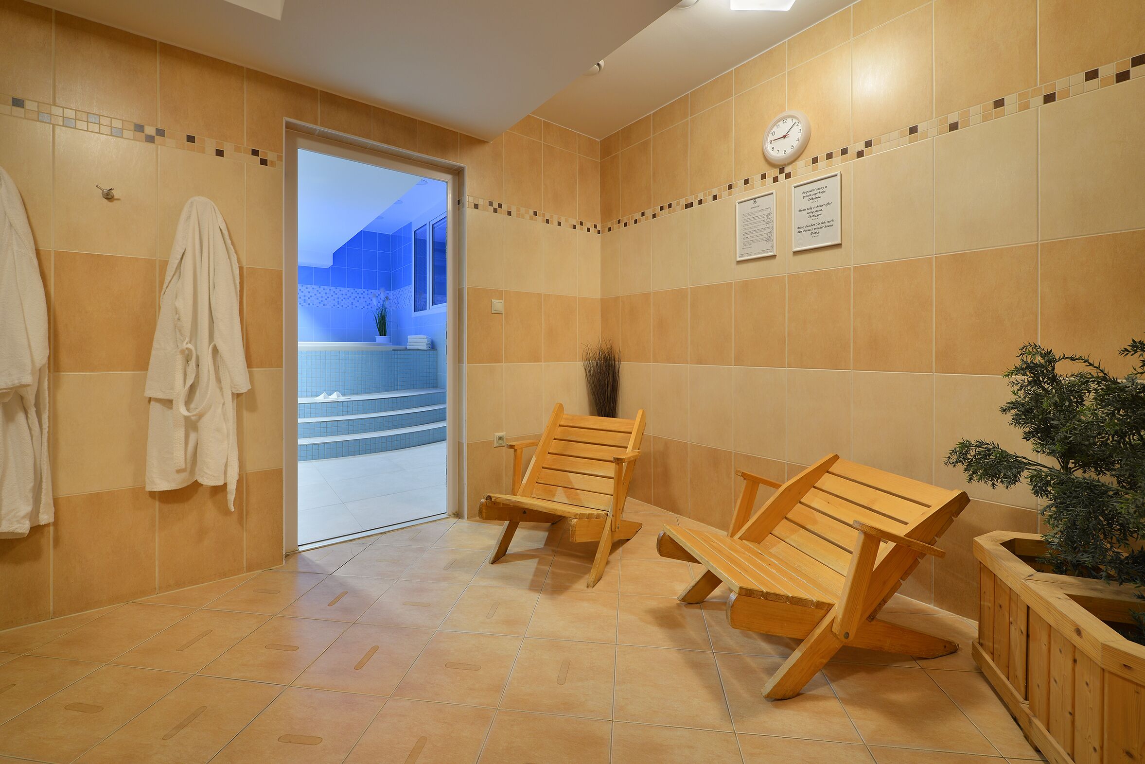 A bathroom with wooden chairs, a clock, and a potted plant.