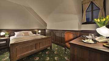 A bedroom with a wooden bed, a desk with a telephone, and a window with curtains.