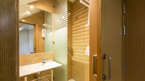 A modern bathroom with a wooden vanity, a glass shower enclosure, and a walk-in shower. - Di Carlo Hotels Madrid (Madrid)