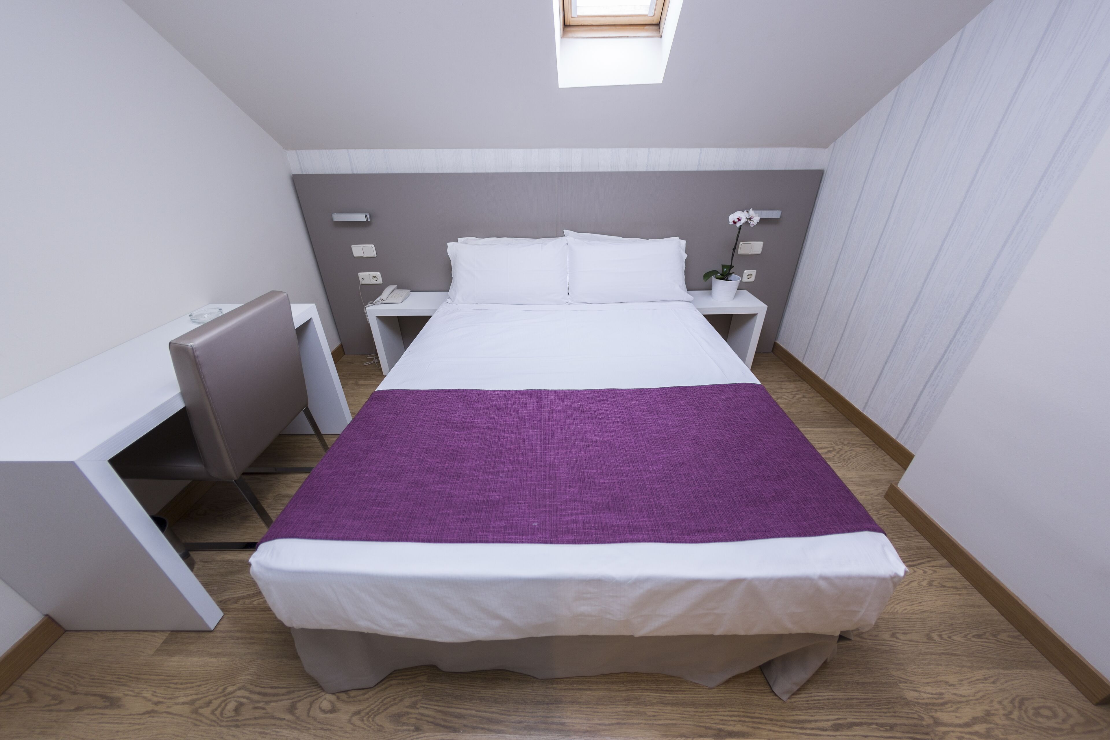 Quarto moderno com cama, escrivaninha e mesa de cabeceira.