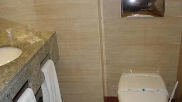 Un baño con encimera de granito, lavabo, espejo y retrete.