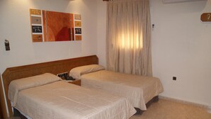 Ein Schlafzimmer mit zwei Betten, einem hölzernen Kopfteil, einem Nachttisch und einem Wandbild.