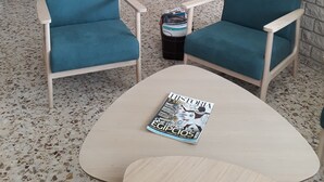 Ein großzügiger Wohnbereich mit zwei blauen Sesseln, einem Couchtisch und einer Zeitschrift darauf.