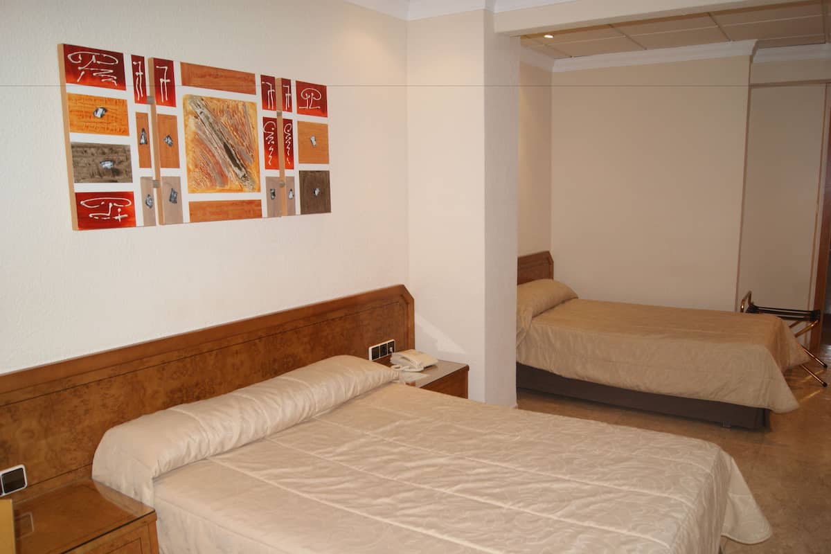 Habitación de hotel con dos camas, cabecero de madera, una obra de arte en la pared y una mesita de noche con un teléfono.