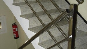 Eine Treppe mit Metallhandläufen und einem an der Wand befestigten Feuerlöscher.