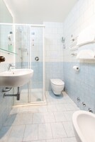 A bathroom with a glass shower enclosure, a white sink, a toilet, and a bathtub.