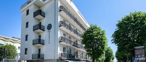 Un hotel de varios pisos con balcones, una entrada cubierta y un cartel que indica una distancia de 30 metros para estacionamiento.