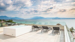 A rooftop terrace with a pool, lounge chairs, and a view of the sea and mountains. - Hotel Bonotto (Desenzano del Garda)