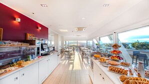 A modern hotel kitchen with a buffet area, large windows, and a view of the city. - Hotel Bonotto (Desenzano del Garda)