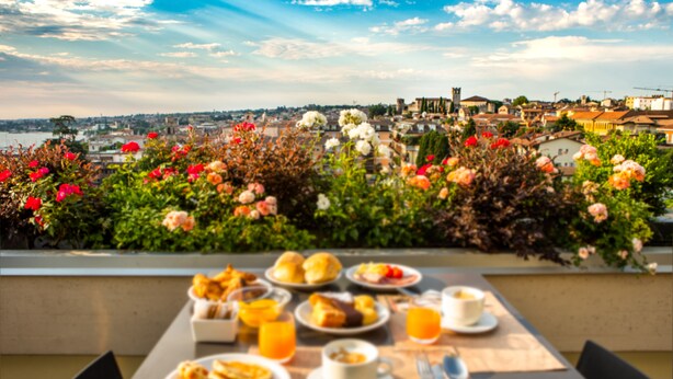 A table set with breakfast items and a view of a cityscape. - Hotel Bonotto (Desenzano del Garda)