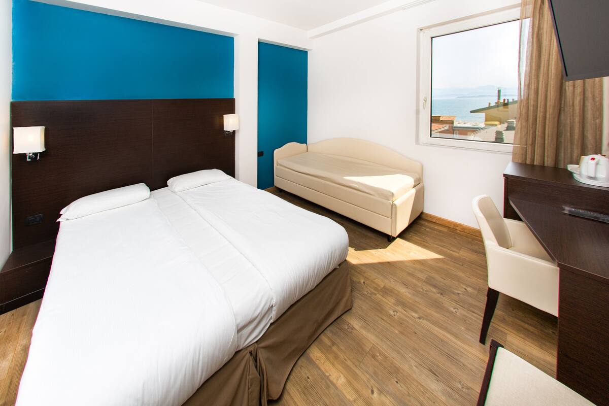 Une chambre d’hôtel avec un grand lit, un lit plus petit, un bureau et une chaise.