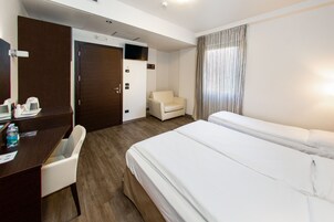 Habitación de hotel con cama, escritorio, silla y televisor.