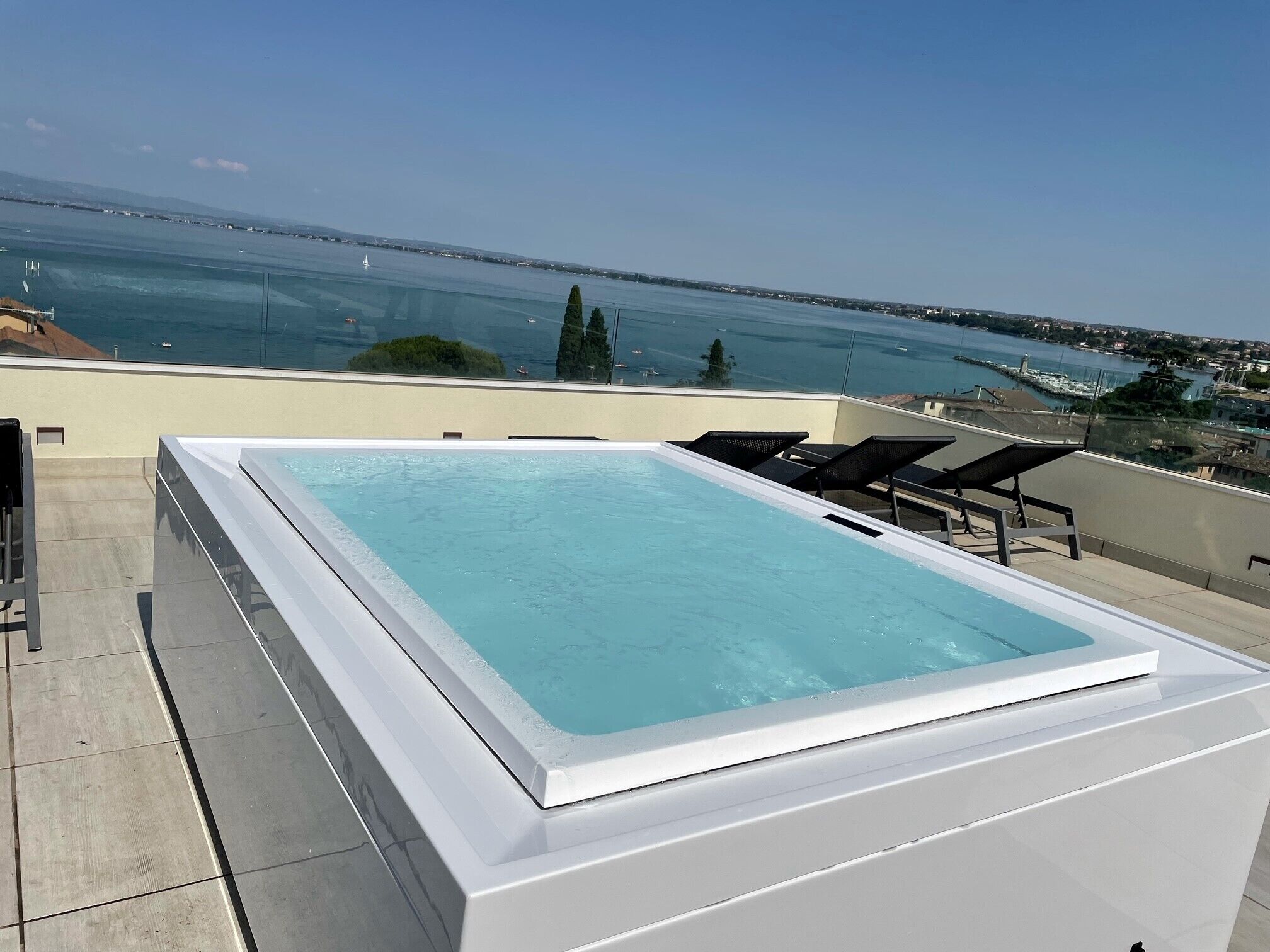 A rooftop swimming pool with a clear view of the sea and distant cityscape.