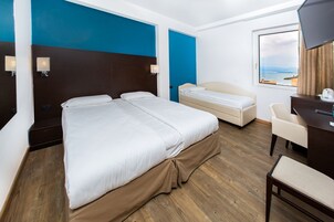 Una habitación de hotel con una cama grande, una cama más pequeña, un escritorio y una silla.