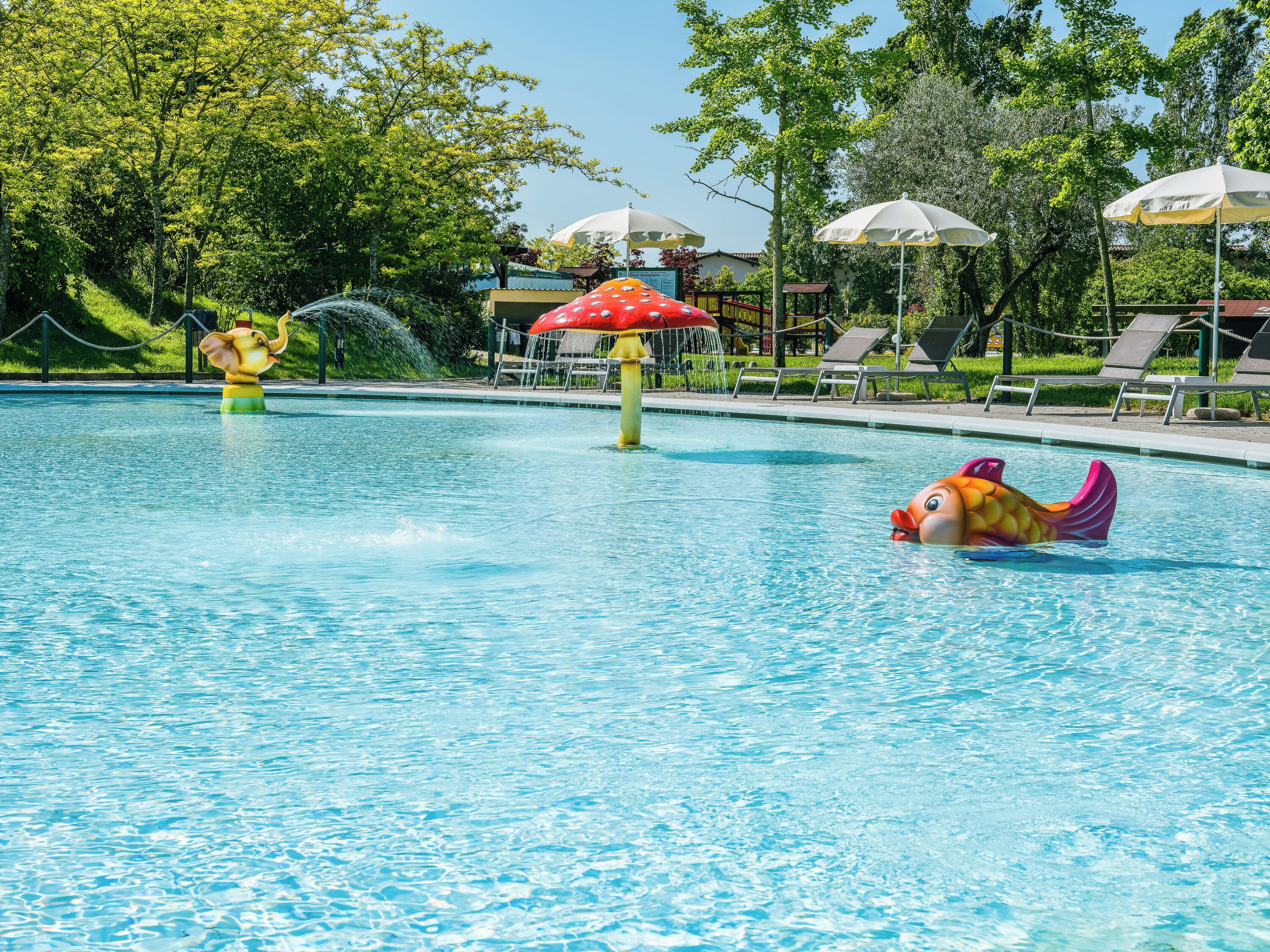 A swimming pool with water features and lounge chairs.